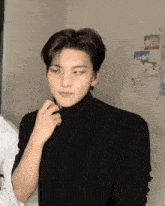 a man wearing a black turtleneck sweater is standing in a room .