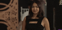 a woman in a black dress is smiling in front of a sign that says ' a ' on it