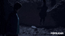 a person standing in a dark room with the word popsugar written on the bottom