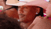 a man wearing a pink cowboy hat and earrings looks at something