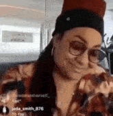 a woman wearing glasses and a hat is smiling while sitting on an airplane .