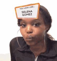 a woman wearing a sign on her head that says selena gomez
