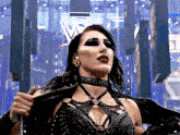 a woman wearing a choker and a black jacket is standing in front of a large w logo