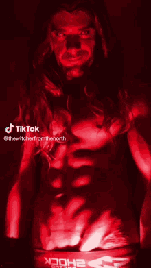 a man with long hair is standing in a dark room with a red light behind him and the words tiktok on the bottom