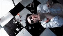 a man laying on a checkered floor with a cigarette in his mouth