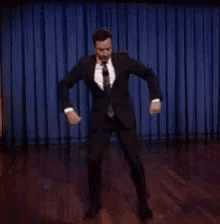 a man in a suit is dancing on a stage