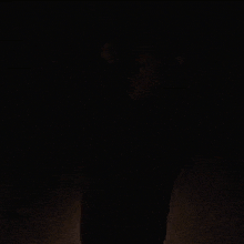 a woman wearing a black sweater is standing in the dark