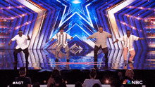 a group of men are dancing on a stage with a nbc logo on the bottom right