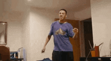 a man wearing a purple shirt is dancing in a living room .