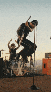 a man in a black shirt is jumping in the air while playing a guitar