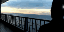 a person is standing on a balcony overlooking the ocean