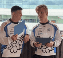 two men wearing sweaters with honda tudor and mobil logos
