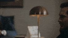 a man is sitting at a table with a lamp on it .