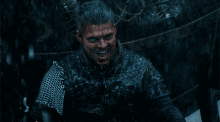 a man with chain mail around his arm is smiling in the rain