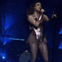a woman is singing into a microphone while wearing fishnet tights