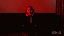 a little girl is sitting in a dark room with red lights behind her .