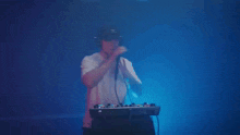 a man wearing a hat with the letter x on it sings into a microphone
