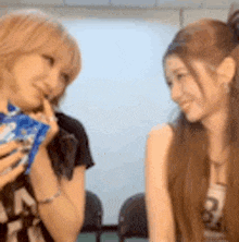 two women are sitting next to each other in a room and talking .