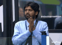 a man in a blue shirt is clapping his hands in front of a screen that says imgplay on it