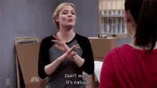 a woman is talking to another woman in a room and making a gesture with her hands .
