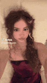 a woman in a red dress with a flower in her hair has a tiktok icon on her face