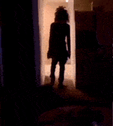 a person with dreadlocks is standing in a dark room in front of a refrigerator .