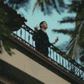 a man standing on a balcony with a wrought iron railing that has the letter g on it