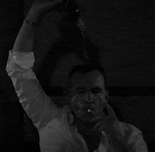 a man in a white shirt is drinking from a glass