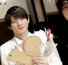 a man in a white shirt is holding a cardboard squirrel .