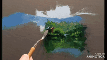 a person is painting a landscape with the words made in animotica on the bottom right