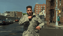 a man in a military uniform is running down a street with a one way sign in the background