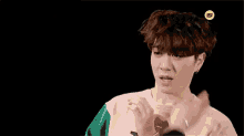 a young man in a pink and green sweater is making a funny face with his hands .