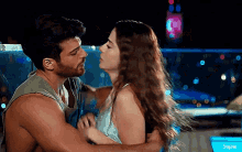 a man and a woman are hugging and kissing in front of a pool .