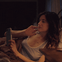 a woman is laying on a bed looking at her phone