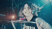 a man with a tattoo on his arm is playing drums and smiling
