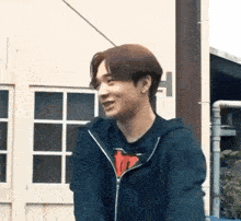 a young man wearing a blue hoodie is standing in front of a building .