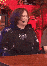 a man with purple hair is wearing a black shirt with a pentagram on it and a microphone