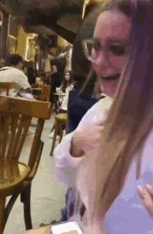 a woman wearing glasses is sitting at a table in a restaurant with other people