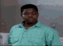a man in a green shirt is standing in front of a toilet and making a funny face .