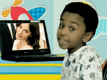 a young boy sitting in front of a toshiba laptop