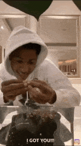 a man in a white hoodie is sitting at a table with a cake in front of him and says i got you