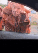 an elderly woman wearing glasses is looking out of a car window .