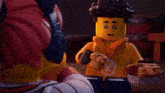 a lego man wearing an orange hoodie with a x on it