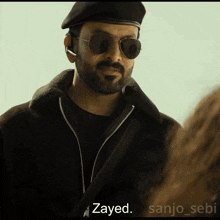 a man with a beard wearing sunglasses and a black beret says zayed