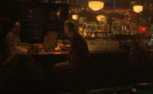 a man sits at a bar drinking from a bottle