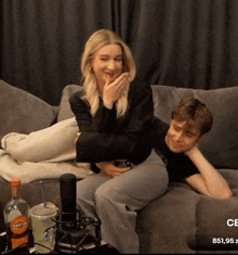 a man and a woman are sitting on a couch with a martini bottle in the background