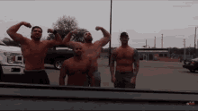 a group of men flexing their muscles in front of a truck