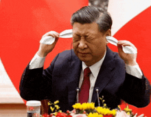 a man in a suit and tie is covering his ears with a napkin
