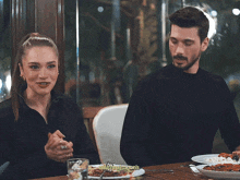 a man and a woman are sitting at a table with plates of food and the words minimalmoons on the bottom