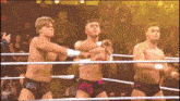 three wrestlers are in a ring and one has the letter b on his underwear